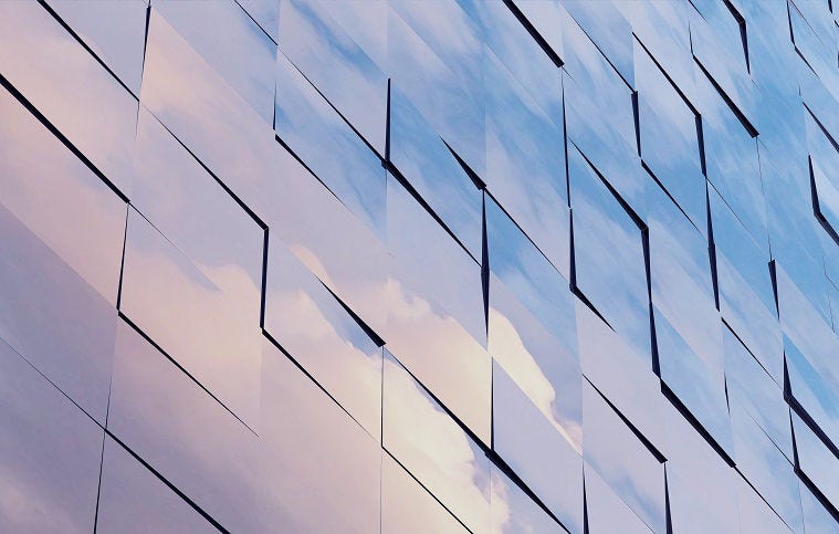 clouds reflected on glass office building