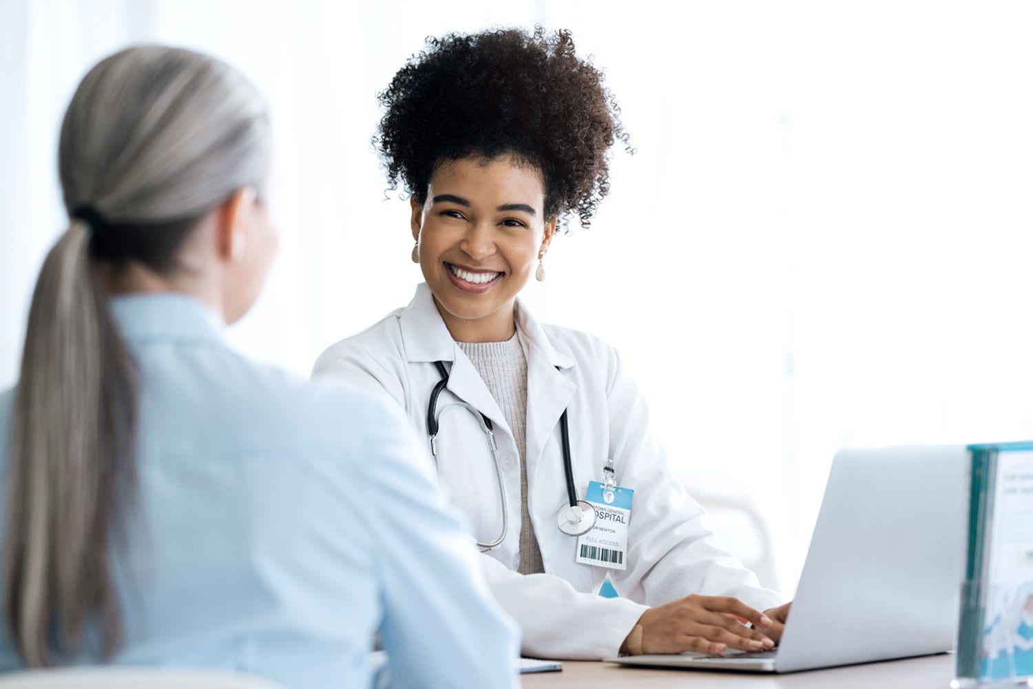 Doctor working on laptop and looking at patient Doctor working on laptop and looking at patient