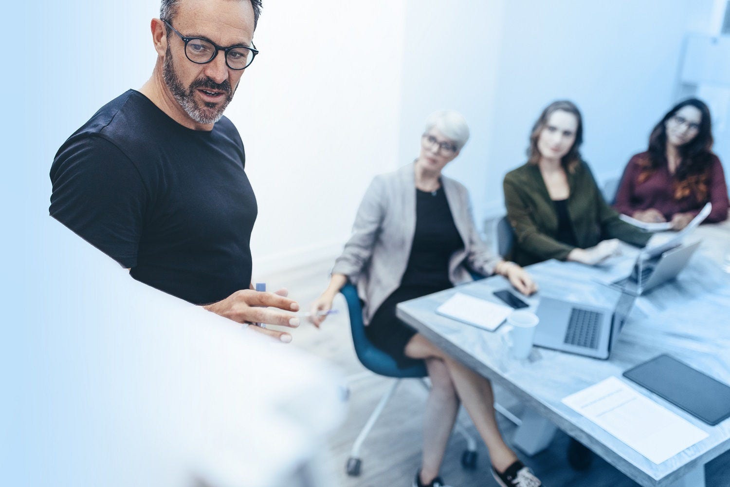 Entrepreneur doing presentation in meeting room Businessman giving presentation on white board to colleagues in conference room. Entrepreneur doing presentation in meeting room.
