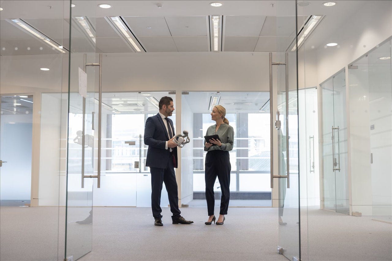 Man Woman Discussing in Hallway Lady with a tablet smiling